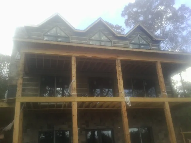 Dormers and porch framing on a large log home under construction — Roof Coating work by our crew in Port Sanilac