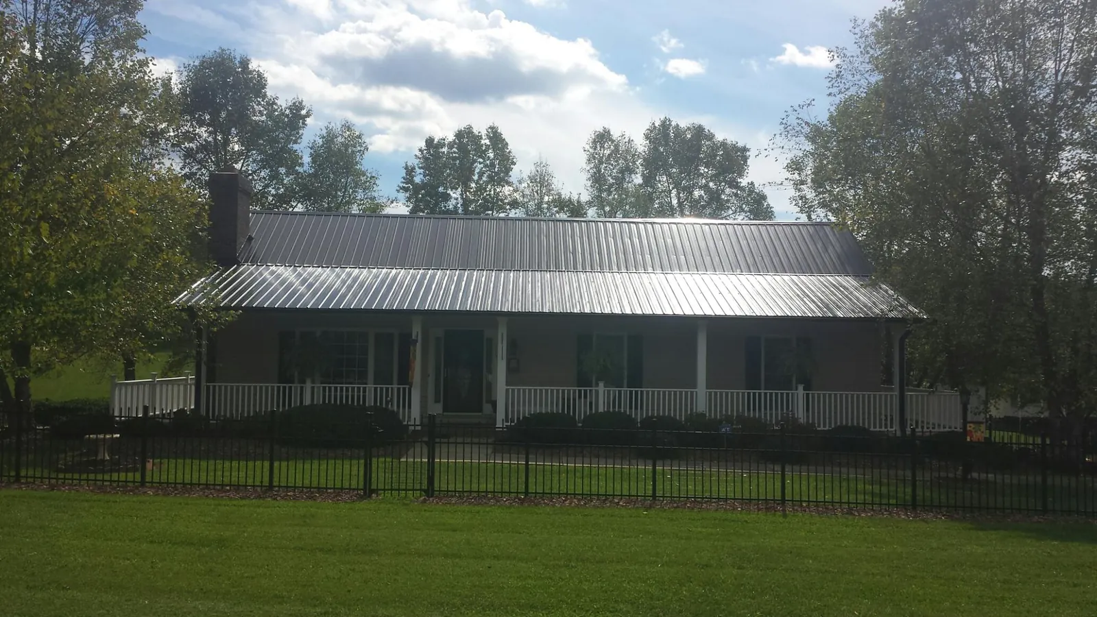 Gray metal roof on a brick ranch with a full width front porch — Gutter Guard Installation work by our crew in Port Sanilac