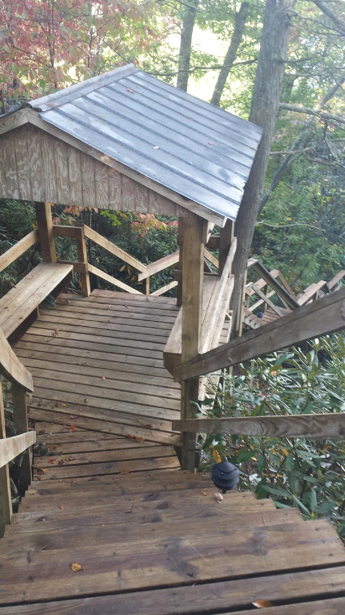 Metal roofed shelter over wooden steps on a wooded walkway — Skylight Repair & Installation work by our crew in Port Sanilac