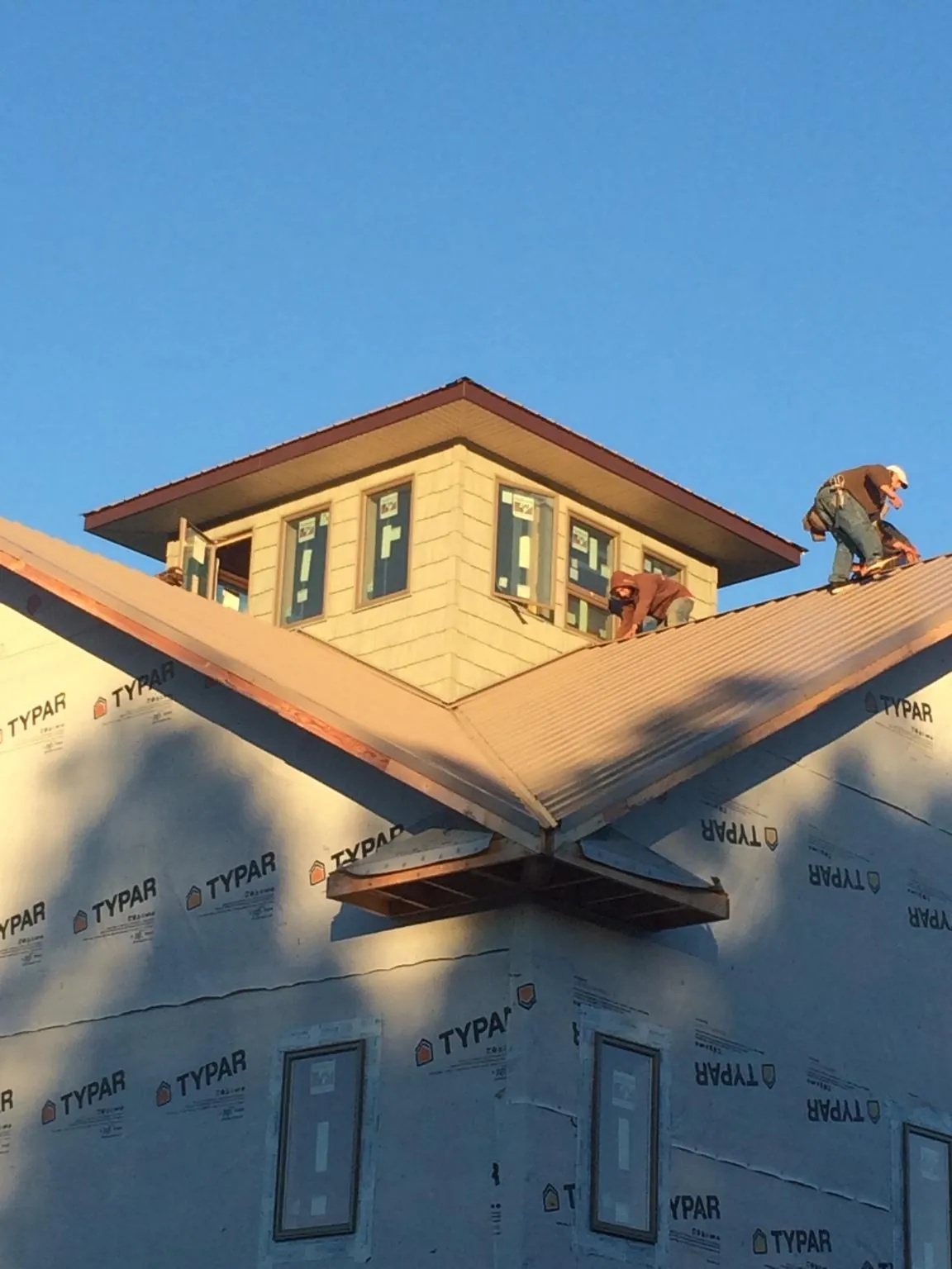 Roofers working around a rooftop cupola on a new metal roof at sunset — Roof Waterproofing in Port Sanilac by Roofing Brothers